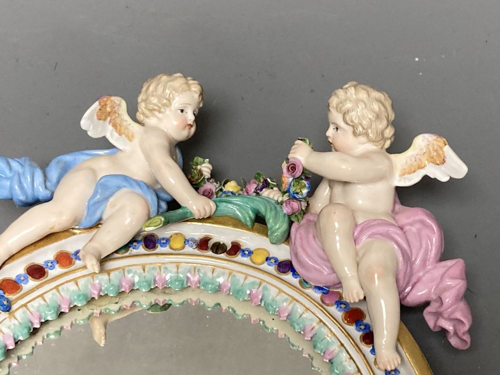 A 19th century Meissen porcelain framed oval mirror surmounted with two angelic figures, height 22cm